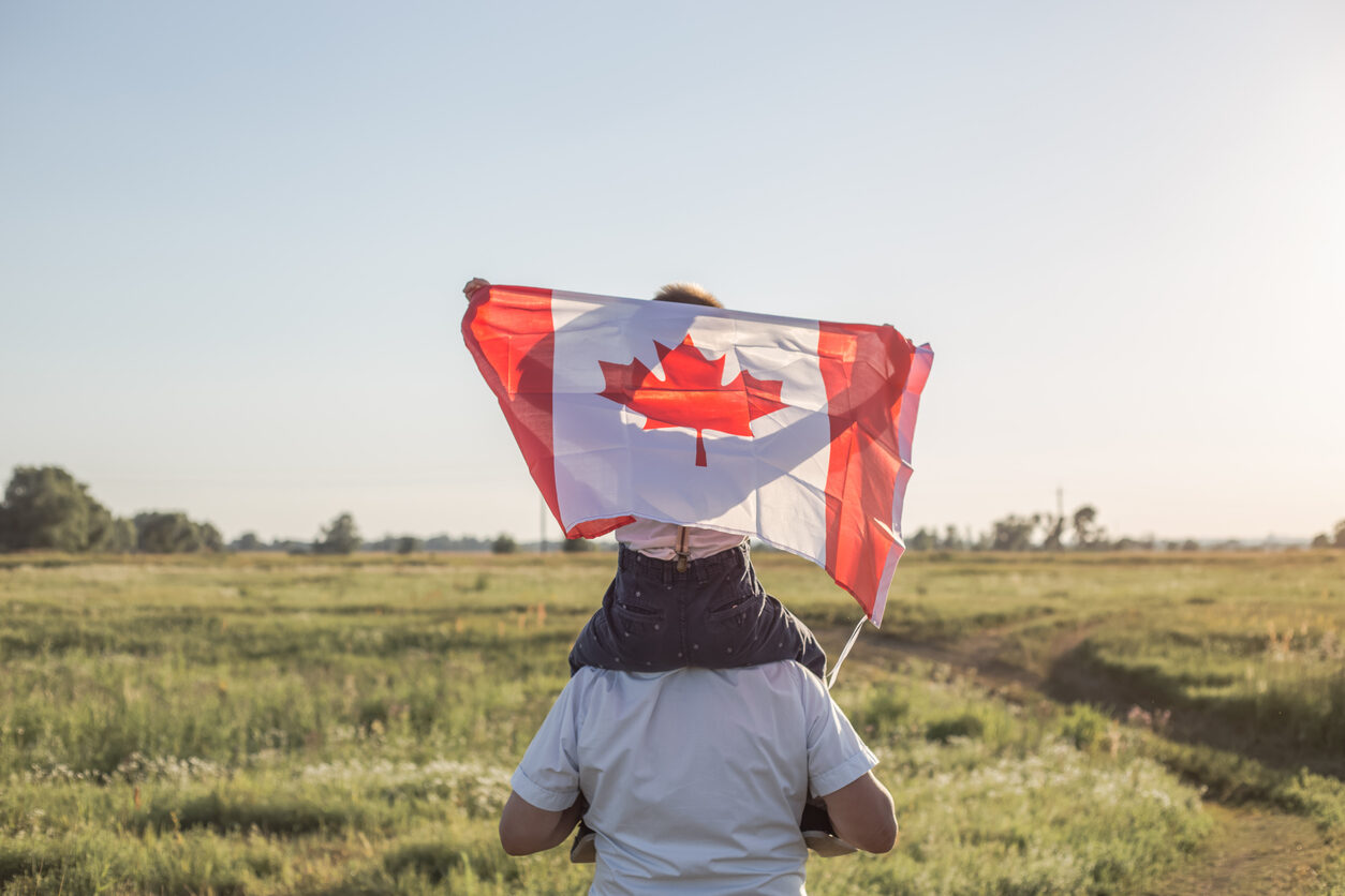 child holding canadian flag sitting on dads shoulders