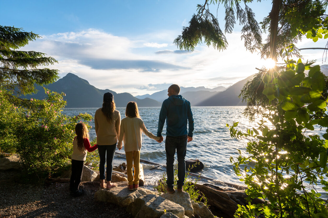 family overlooking body of water and mountains